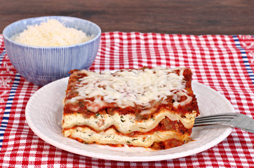 A serving of Lasagna with a side of Parmesan.