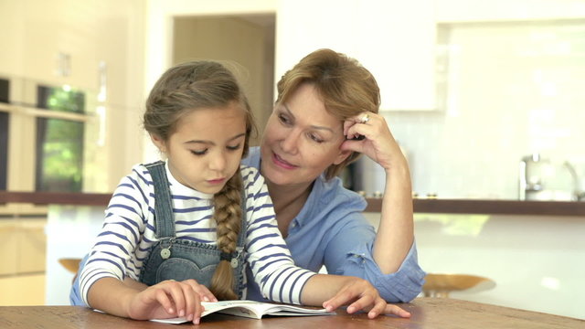 Grandmother Helping Granddaughter With Reading At Home