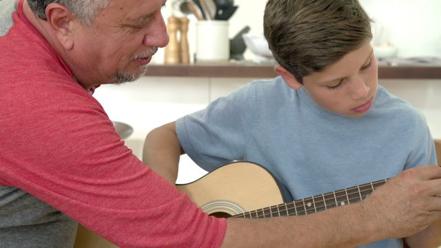 Grandfather Teaching Grandson To Play Guitar