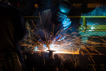 Welder working in a steel factory with sparks flying