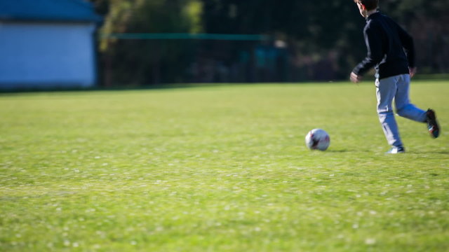 Kid on soccer field running around and kicking ball