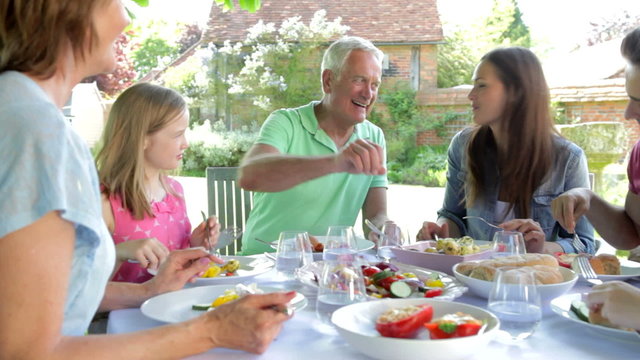 Multi-Generation Family Sitting Outdoors Around Table Eating