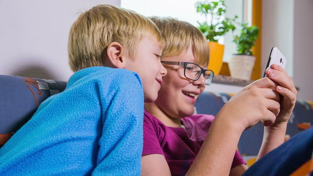 Child interested in what brother is playing on smartphone