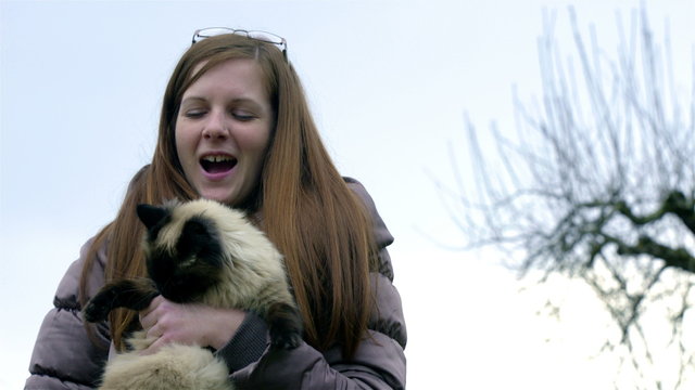 Woman holding cat while it bites her hand