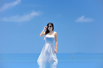 Fototapeta na wymiar 海辺に立つワンピースの若い女性