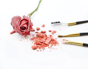 cosmetic brushes, pink powder and a rose on the white background