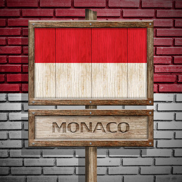 Monaco flag wooden sign with brickwall background