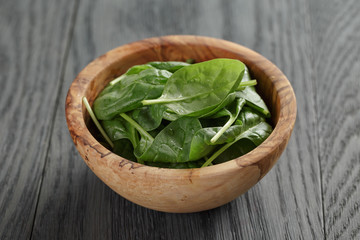 fresh spinach leaves in olive bowl on wood table