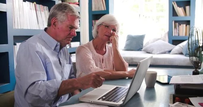 Senior Couple In Home Office Looking At Laptop