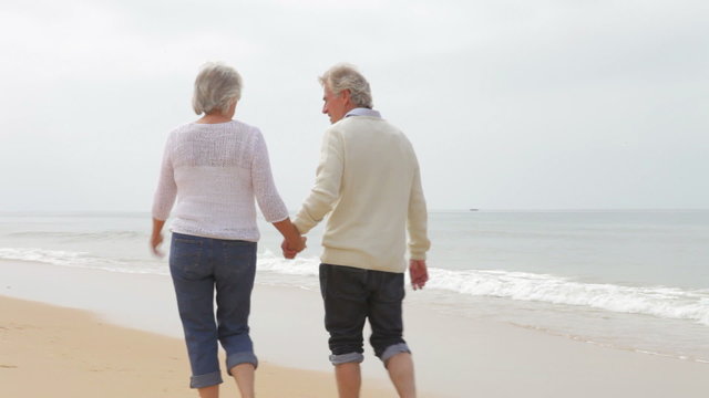Senior Couple Walking Along Misty Beach