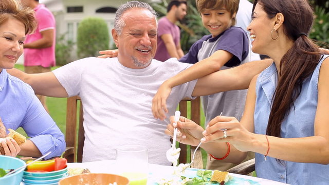 Multi Generation Family Enjoying Meal In Garden Together