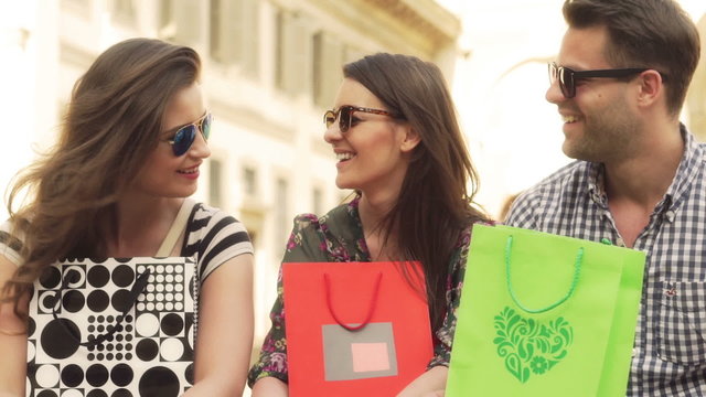 Friends holding shopping bags and smiling to the camera
