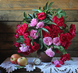 Красные и розовые розы в корзине на фоне из досок