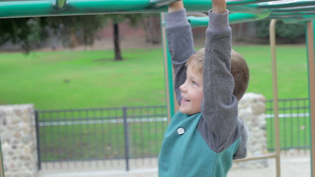 Young Boy Playing On Climbing Frame In Playground