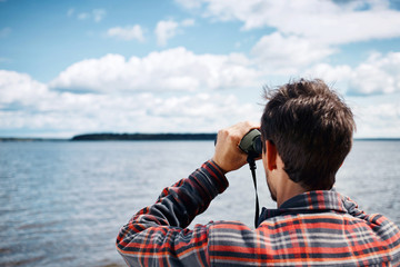 Close up back portrait man looks through binoculars while fishin