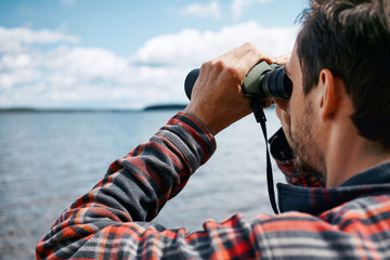 Close up back portrait man looks through binoculars while fishin
