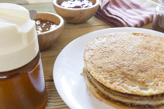 Delicious stack of pancakes with chocolate cream, bowls of jam and honey