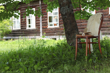 Fototapeta na wymiar book on a chair in the park with tea and flowers