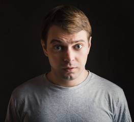 Fototapeta premium Surprised face. Dark background. Color toned image.