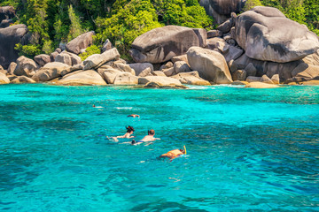 three traveller snorkeling in the tropical sea at sunny day