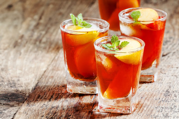 Peach Tea with pieces of fruit and mint on a wooden background,