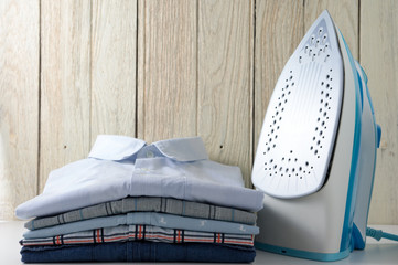Ironing clothes with shirts and iron with wood background
