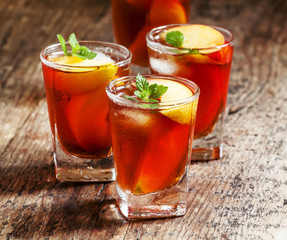 Peach Tea with pieces of fruit and mint on a wooden background,