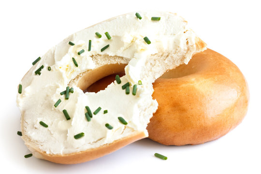 Plain bagel spread with cream cheese and chives, bite missing. I