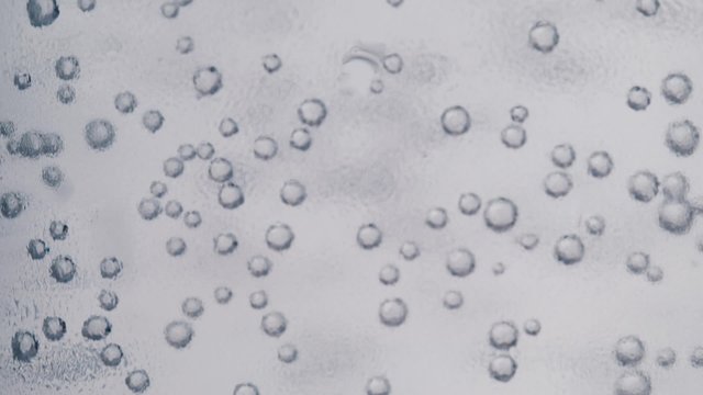 Super close-up of gas bubbles in the water outside the glass condensate