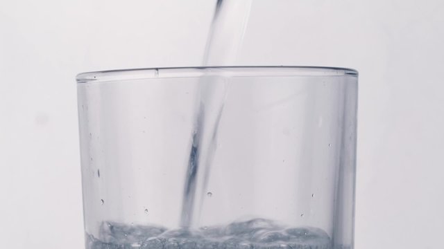 Carbonated water is poured into a glass close-up on a white background
