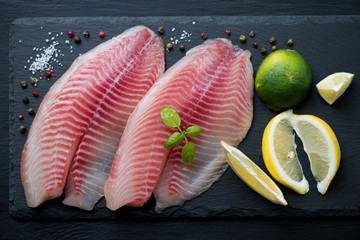 Close-up of raw fresh tilapia filet with seasonings, studio shot