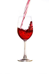 Pouring red wine in a wine glass, isolated on a white background