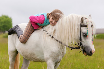 The young girl lies on the white horse back and smiling  Outdoors