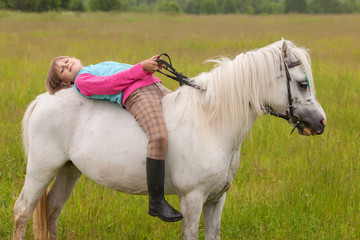 The little girl lay on her back white horse and smiling  Outdoors