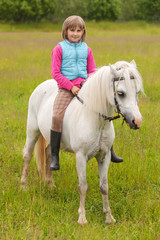 Young girl child sitting astride a white horse and smiling  Outdoors