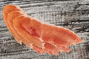 Prosciutto Slices on very old Wooden Background.