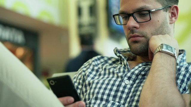 Man sitting on the airport and using cellphone, steadycam shot
