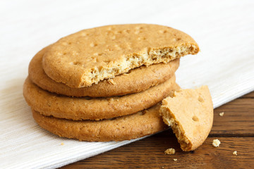 Stack of sweetmeal digestive biscuits on dark wood and napkin.