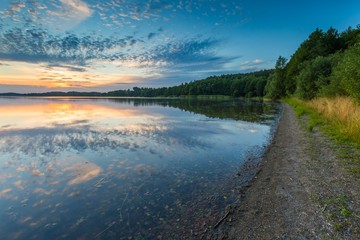 Beautiful lake at sunset landscape with cloudy sky reflecting in water