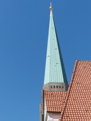 Kirchturmspitze der Altstädter Nicolaikirche mit Grünspan vor blauem Himmel im Sonnenschein in...