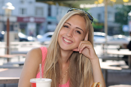 Woman sits in a cafe and smiling outdoors