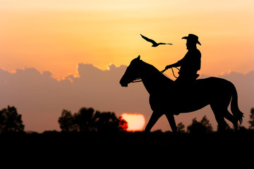 silhouette of Cowboy sitting on his horse at river full moon after sunset background