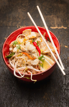 Asian noodles with chopstick, chicken and sprouts in red bowl