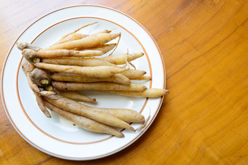 Fingerroot herb on white dish, wood background