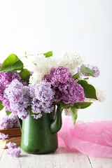 Beautiful lilac in pitcher on white wooden background