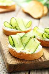 Tasty fresh bruschetta with cucumber on cutting board on grey wo