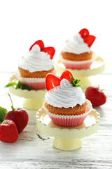 Tasty cupcake with strawberry on cake stand on white wooden back
