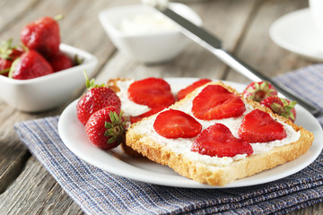 Fresh toast with cream cheese and strawberry on grey wooden back