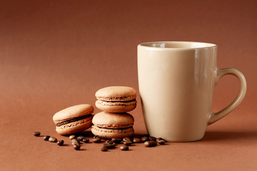 French chocolate macaroons with coffee beans on brown background