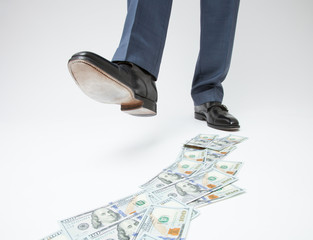 Feet of man in black shoes going by money track
